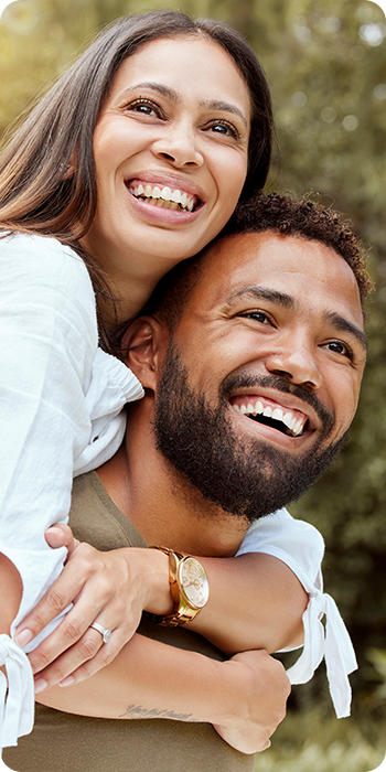 couple smiling with woman on man's shoulders